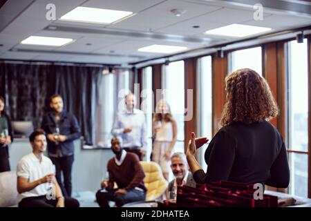 Businesswoman giving speech to coworkers during office party after work Stock Photo