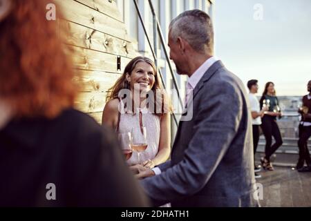 Smiling businesswoman talking with coworkers in party on terrace Stock Photo