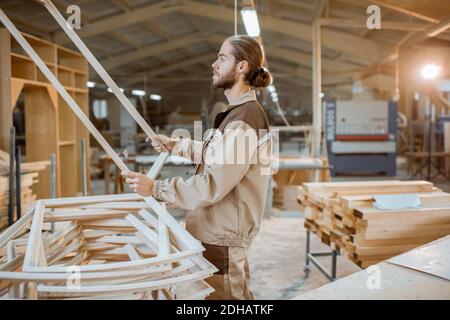 Handsome carpenter checking the quality of the window frame before the paint at the carpentry workshop