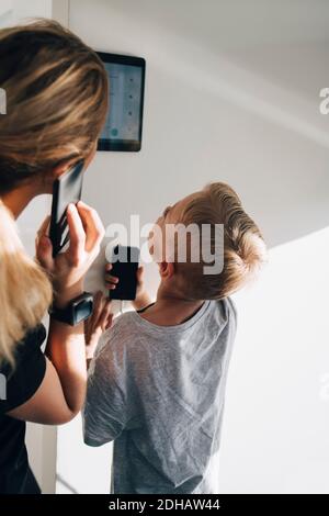 Siblings using digital tablet mounted on wall at home Stock Photo