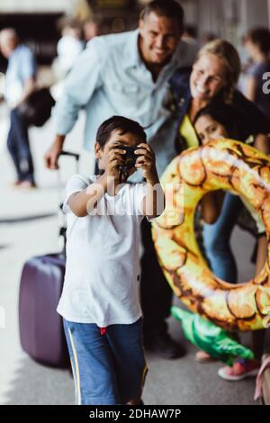 Boy taking selfie with family on camera at train station during vacations Stock Photo