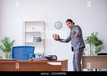 Young male employee with rugby ball in the office Stock Photo