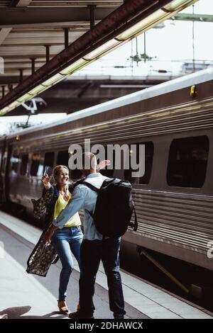 Cheerful couple embracing by train on railroad station platform Stock Photo