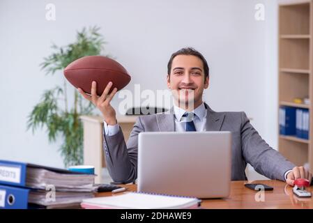 Young male employee with rugby ball in the office Stock Photo