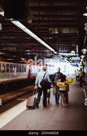 Parents and children walking with luggage on railroad station platform Stock Photo