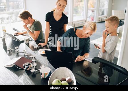High angle view of family using technologies at dining table in room Stock Photo