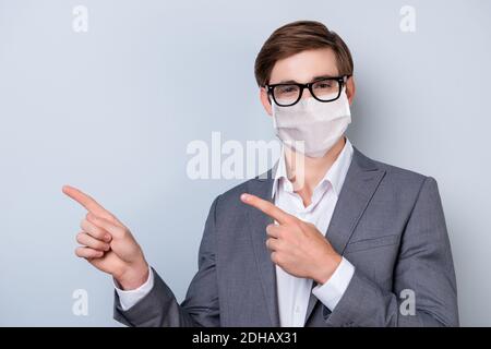 Close-up portrait of nice healthy guy in suit and spectacles pointing copy space wearing safe mask isolated over gray color background Stock Photo