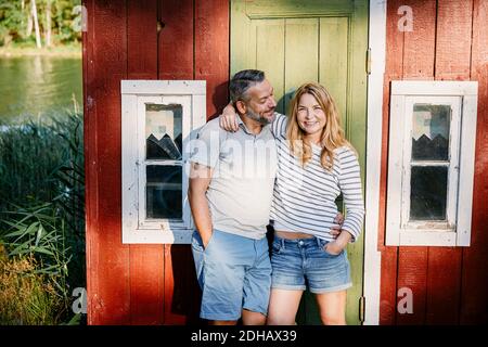 Mature man looking at cheerful female partner while embracing her against door Stock Photo