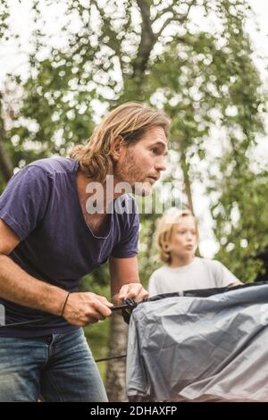 Mature man pitching tent during summer vacation Stock Photo