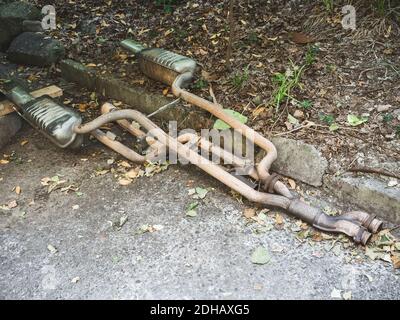 The old exhaust system from the car lies on the asphalt near the curb on the street Stock Photo