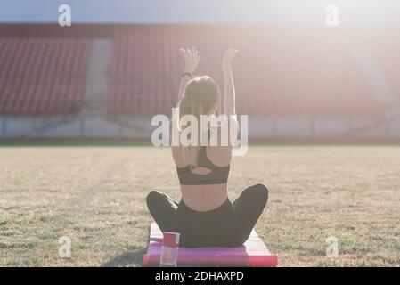 Young female alone at the stadium doing yoga Stock Photo