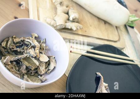 Bowl with dried mushrooms, ginger and daikon on the background Stock Photo