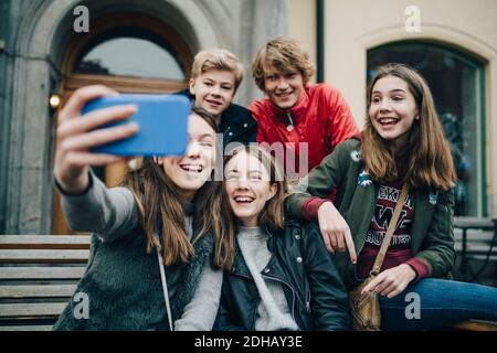 Smiling friends taking selfie through mobile phone in city Stock Photo