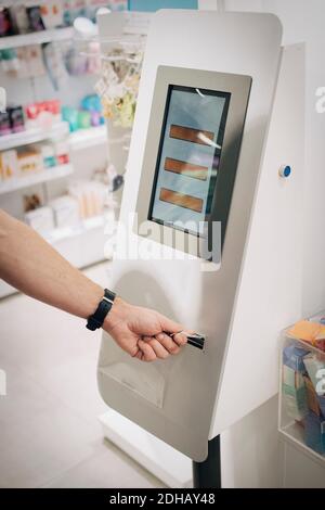 Cropped hand of male customer using kiosk at pharmacy store Stock Photo