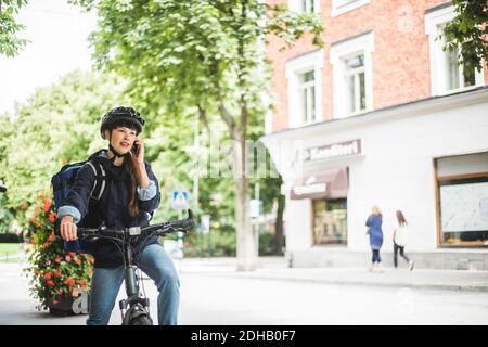 Food delivery woman talking on smart phone at street in city Stock Photo