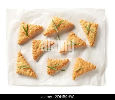 freshly baked cheese cookies decorated with rosemary on baking paper sheet isolated on white background, top view Stock Photo