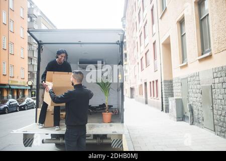 Male and female movers unloading box from truck on street in city Stock Photo