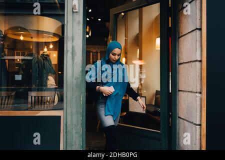Young woman wearing hijab leaving store in city Stock Photo