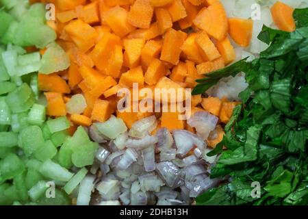 Mixed vegetables with brunoise cut for sautéing on a wooden cutting board (carrots, celery, onion and shallot) Stock Photo