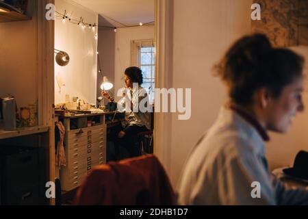 Technician working at desk with woman sitting in foreground Stock Photo