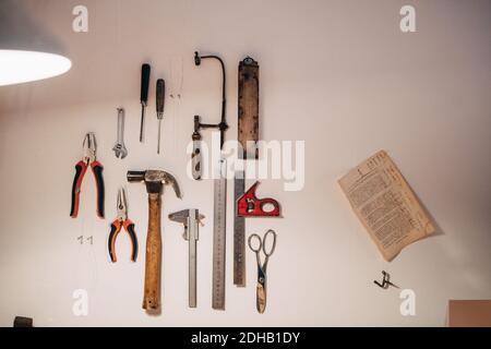 Various work tools hanging on wall at workshop Stock Photo