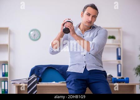 Young handsome male employee doing exercises in the office Stock Photo