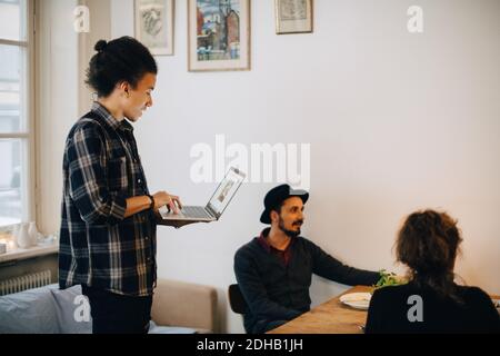 Businessman using laptop while discussing with male and female colleagues at creative office Stock Photo