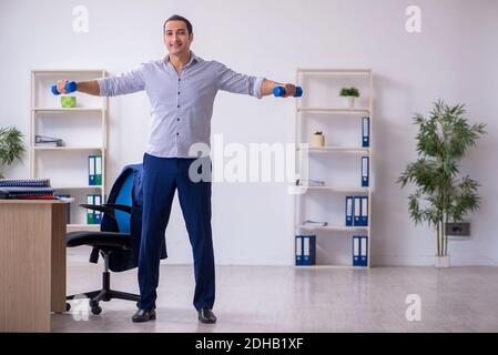 Young handsome male employee doing exercises in the office Stock Photo