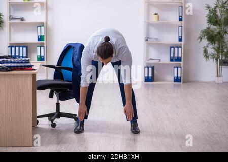 Young handsome male employee doing exercises in the office Stock Photo
