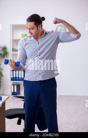 Young handsome male employee doing exercises in the office Stock Photo