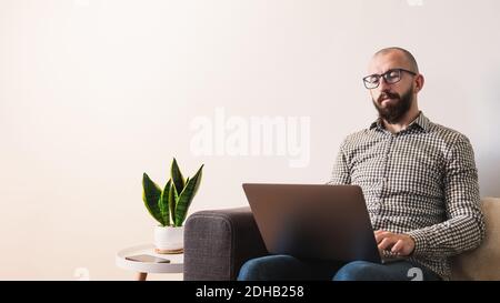 Young male adult works on his laptop at home, modern minimalistic interior Stock Photo
