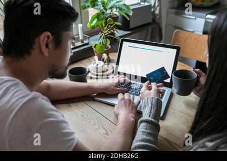 Couple having coffee and using credit card while shopping online through laptop at home Stock Photo
