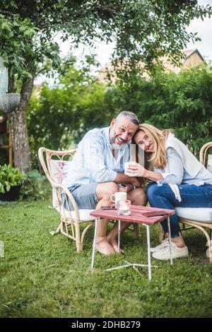 Portrait of loving happy mature couple having coffee in backyard Stock Photo