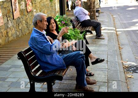 Older couple talking sitting on roadside bench Stock Photo
