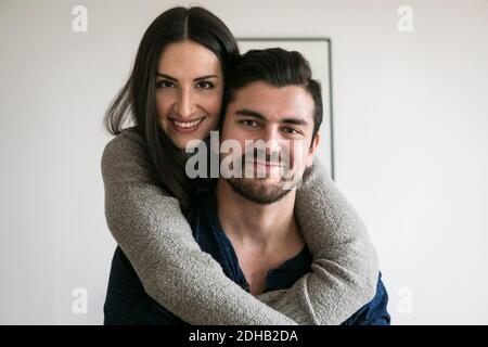 Portrait of affectionate smiling young couple standing against wall at home Stock Photo