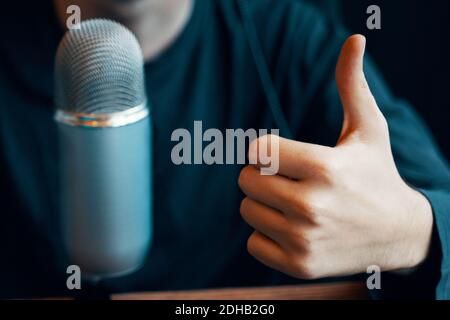 The guy is live on the Internet with professional microphone in the Podcast studio. Like gesture. Radio show concept. Vintage mic for broadcast. Stock Photo