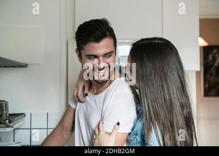 Smiling couple looking at each other while standing in kitchen Stock Photo