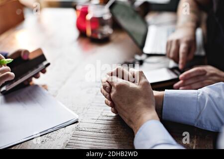 Cropped image of business people using mobile phone and doing paperwork at table in restaurant Stock Photo