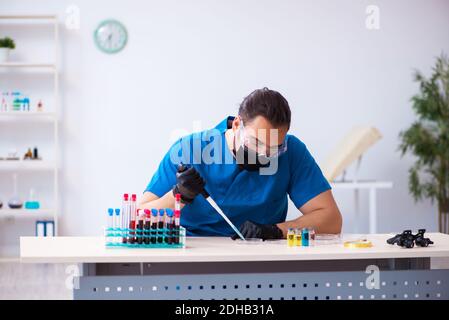Young male biochemist testing blood samples in pandemic concept Stock Photo