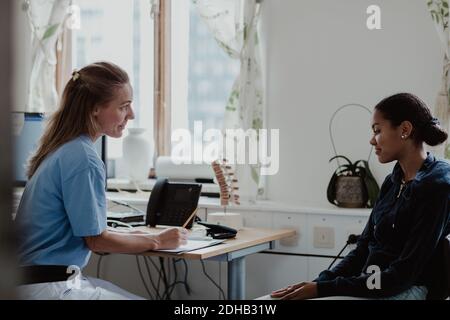 Mature nurse explaining to female patient while sitting at doctor's office Stock Photo