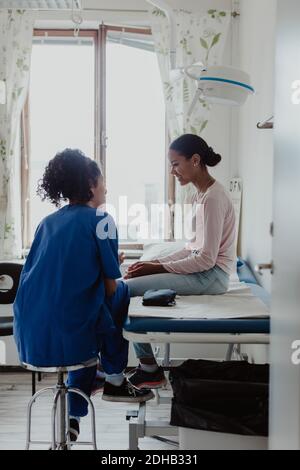 Smiling patient and female doctor discussing in medical room Stock Photo