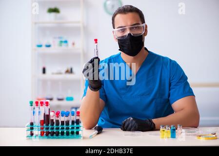 Young male biochemist testing blood samples in pandemic concept Stock Photo