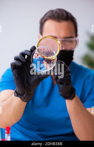 Young male biochemist testing blood samples in pandemic concept Stock Photo