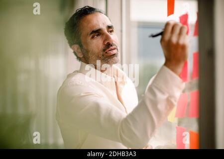 Businessman writing on adhesive note at convention center Stock Photo