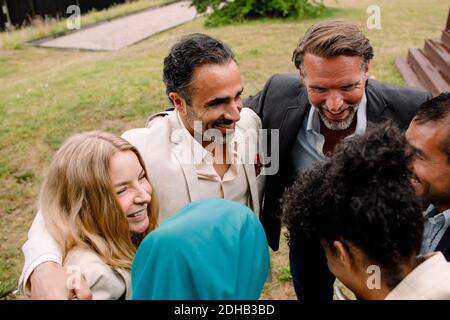 Smiling male and female business professionals huddling in lawn Stock Photo
