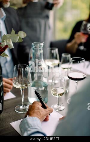 Cropped image of businessman writing on document at table in convention center Stock Photo