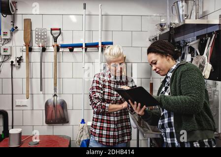 Female workers discussing over digital tablet while working in brewery Stock Photo