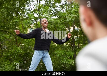 Smiling teenage girl with arms outstretched dancing at park Stock Photo