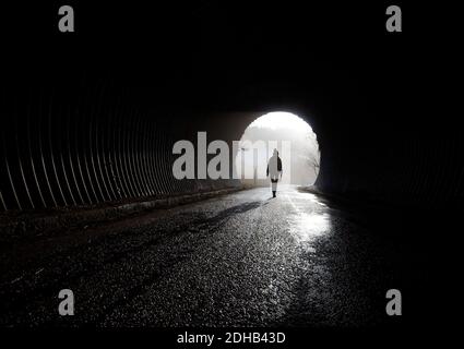 light at the end of tunnel, silhouette walking trough the darkness Stock Photo