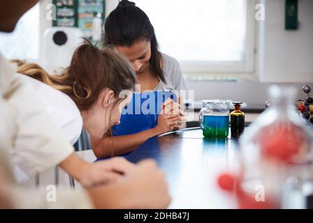 Female students looking at liquid solution in beaker in chemistry laboratory Stock Photo